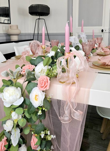 Décoration de table rose et doré Table élégamment dressée avec des fleurs, des bougies roses et des serviettes assorties.
