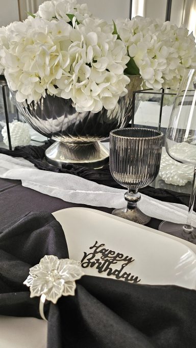 Décoration de table noir et blanc chic – Idée anniversaire élégant Décor de table élégant avec des fleurs blanches et une assiette au message "Happy Birthday".
