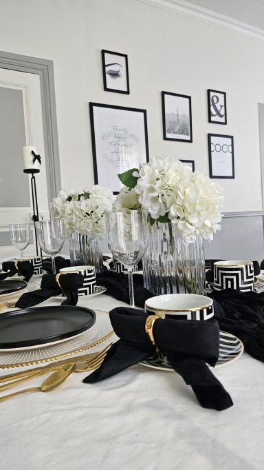 Décoration de table élégante noir et doré – Table enchantée Table dressée avec des fleurs blanches, assiettes noires et décorations élégantes.