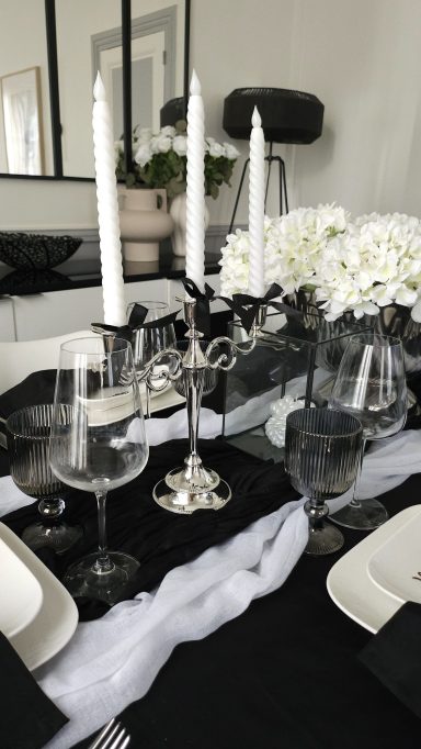 Décoration de table noir et blanc chic – Idée anniversaire élégant Table élégamment dressée avec bougies, verres et décorations florales blanches.