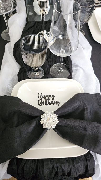 Serviette de table noire élégante Décor de table élégante avec assiette blanche et nœud noir, verres en cristal.